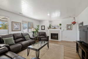Living room with light wood-type flooring, a tiled fireplace, and baseboards