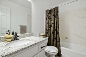 Bathroom featuring toilet, vanity, and shower / bath combo with shower curtain