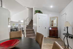 Dining space featuring wood finished floors, stairs, vaulted ceiling, recessed lighting, and baseboards
