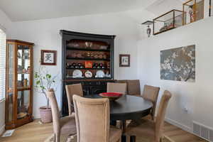 Dining room featuring lofted ceiling, light wood-type flooring, and baseboards