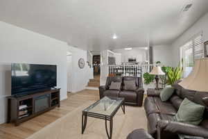 Living area featuring light wood-type flooring, stairs, and baseboards