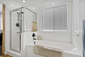 Full bath with a shower stall, a bath, and wood finished floors
