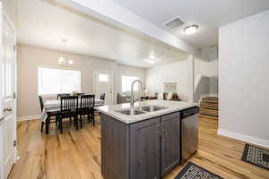 Kitchen with dishwasher, a sink, light wood-type flooring, and baseboards