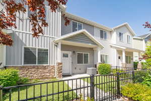 View of front of house featuring board and batten siding, central air condition unit, stone siding, and a porch