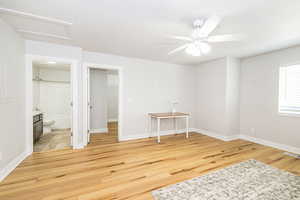 Unfurnished bedroom with light wood finished floors, attic access, baseboards, and connected bathroom
