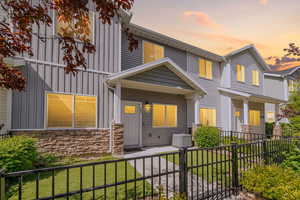 View of front facade with board and batten siding, stone siding, cooling unit, and a porch