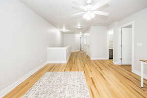 Empty room featuring light wood-style flooring, ceiling fan, and baseboards