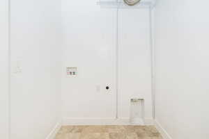 Laundry room featuring washer hookup, hookup for an electric dryer, baseboards, and light stone finish floors