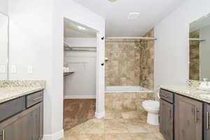 Full bath featuring vanity, baseboards, toilet, a walk in closet, and tiled shower / bath combo