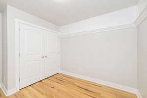 Unfurnished bedroom with light wood-style floors, baseboards, and a closet