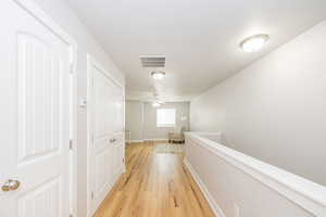 Corridor featuring light wood-style flooring and baseboards