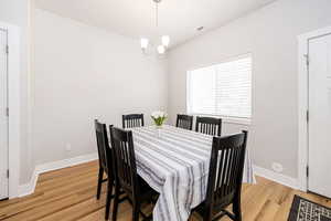 Dining space with light wood finished floors, a chandelier, and baseboards