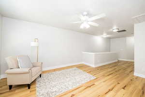 Living area featuring light wood-style flooring, ceiling fan, and baseboards