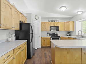 Kitchen with appliances with stainless steel finishes, corner pantry, lofted ceiling, beautiful light natural wood cabinetry, and light countertops