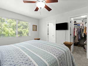 Primary bedroom with walk-in closet and en-suite bathroom in background