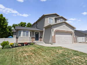 View of front of property featuring stucco siding, concrete driveway, an attached garage,  RV parking, and brick siding