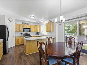Dining room with lofted ceiling, a chandelier, and large kitchen in background