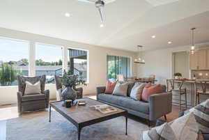 Living room with lofted ceiling, recessed lighting, wood finished floors, ceiling fan, and a chandelier