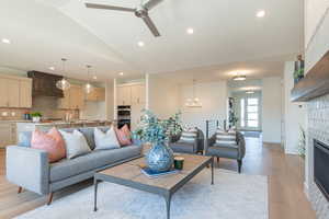 Living room featuring light wood-style floors, recessed lighting, vaulted ceiling, a tile fireplace, and a ceiling fan