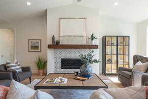 Living room with recessed lighting, wood finished floors, a fireplace, and lofted ceiling