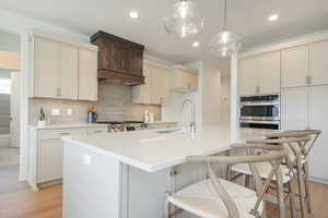 Kitchen featuring light wood-style floors, cream cabinetry, tasteful backsplash, and recessed lighting