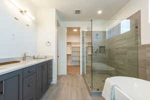 Bathroom with double vanity, a stall shower, a spacious closet, a freestanding tub, and light tile patterned flooring