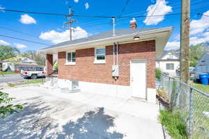 Rear view of house featuring brick siding, fence, and a chimney