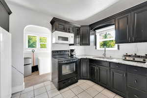 Kitchen with white appliances, a sink, light carpet, light stone counters, and backsplash
