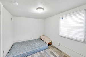 Unfurnished bedroom with light wood-style floors, a textured ceiling, and baseboards