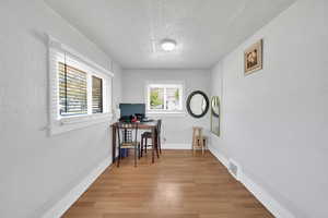 Office area with a textured ceiling, light wood-type flooring, baseboards, and a textured wall