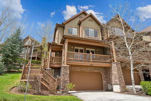 View of front of home featuring an attached garage, driveway, board and batten siding, and stone siding