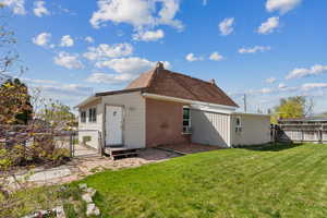 Rear view of house with brick siding, a gate, a chimney, and a patio
