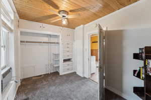 Unfurnished bedroom featuring wooden ceiling, carpet, washer / dryer, a closet, and an AC wall unit