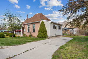 View of side of home with a chimney, brick siding, and concrete driveway