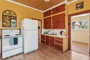 Kitchen featuring white appliances, wooden ceiling, crown molding, light countertops, and light wood-style flooring