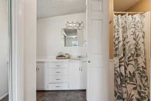 Full bathroom featuring a textured ceiling, vanity, and curtained shower