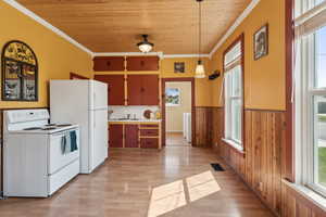 Kitchen featuring white appliances, a wainscoted wall, wooden ceiling, a sink, and plenty of natural light