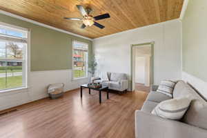 Living room with crown molding, wood ceiling, light wood-style flooring, and a ceiling fan