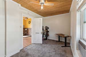 Interior space featuring crown molding, carpet, ceiling fan, wood ceiling, and baseboards