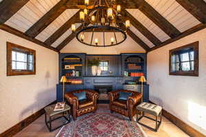 Sitting room featuring a chandelier, healthy amount of natural light, baseboards, a fireplace, and wooden ceiling