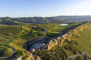 View of mountain backdrop featuring a large body of water and a local golf course