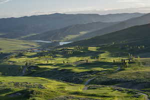 View of mountain background with a nearby body of water and a golf course