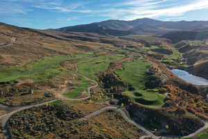 Aerial overview of property's location featuring a mountain backdrop and a local golf course