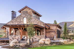 View of front of home featuring stone siding, a chimney, and a mountain view