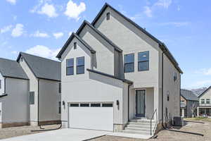 View of front of property featuring driveway, cooling unit, and an attached garage