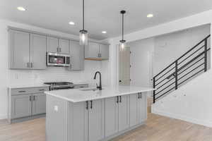 Kitchen with appliances with stainless steel finishes, gray cabinetry, a sink, and recessed lighting