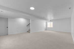 Basement with stairway, baseboards, light carpet, a textured ceiling, and recessed lighting