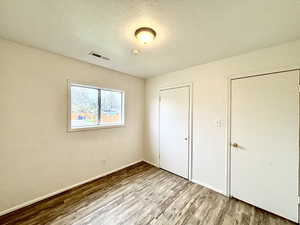 Unfurnished bedroom with wood finished floors and baseboards