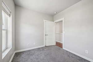 Carpeted spare room featuring baseboards and a smoke detector