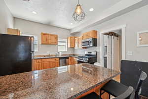 Kitchen with appliances with stainless steel finishes, a sink, a breakfast bar, recessed lighting, and a peninsula
